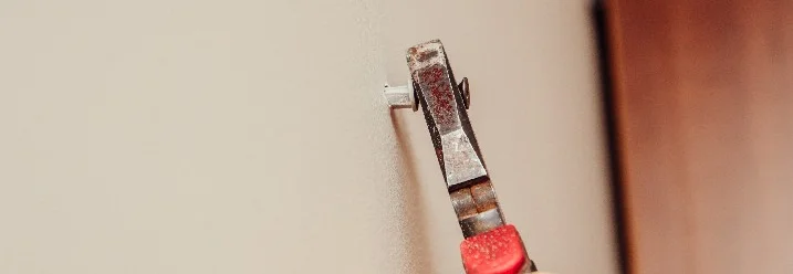 Hand entfernt Dübel mit Zange von Wand